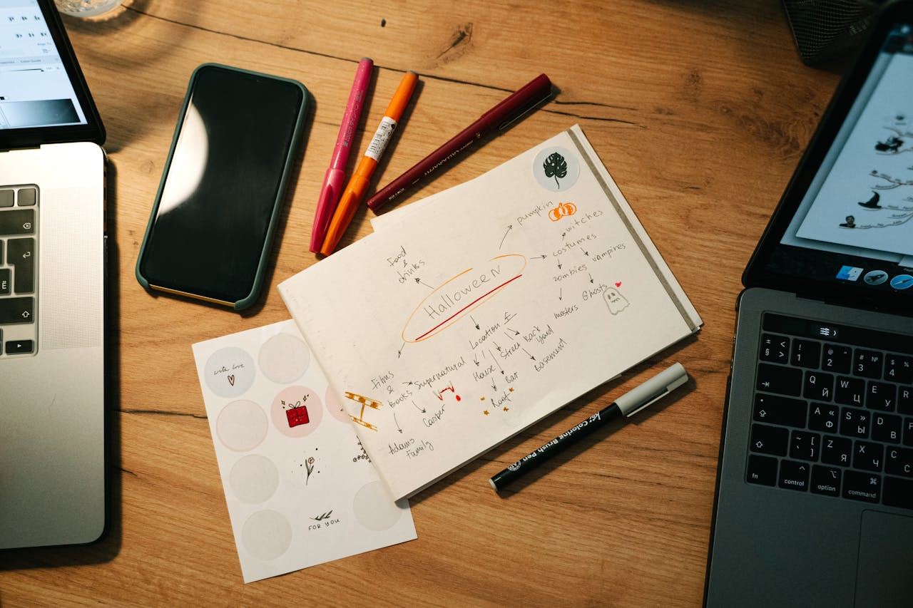 Mastering the First Impression: Your intriguing post title goes here Overhead view of a workspace with notebooks, laptops, and pens, highlighting Halloween project planning.