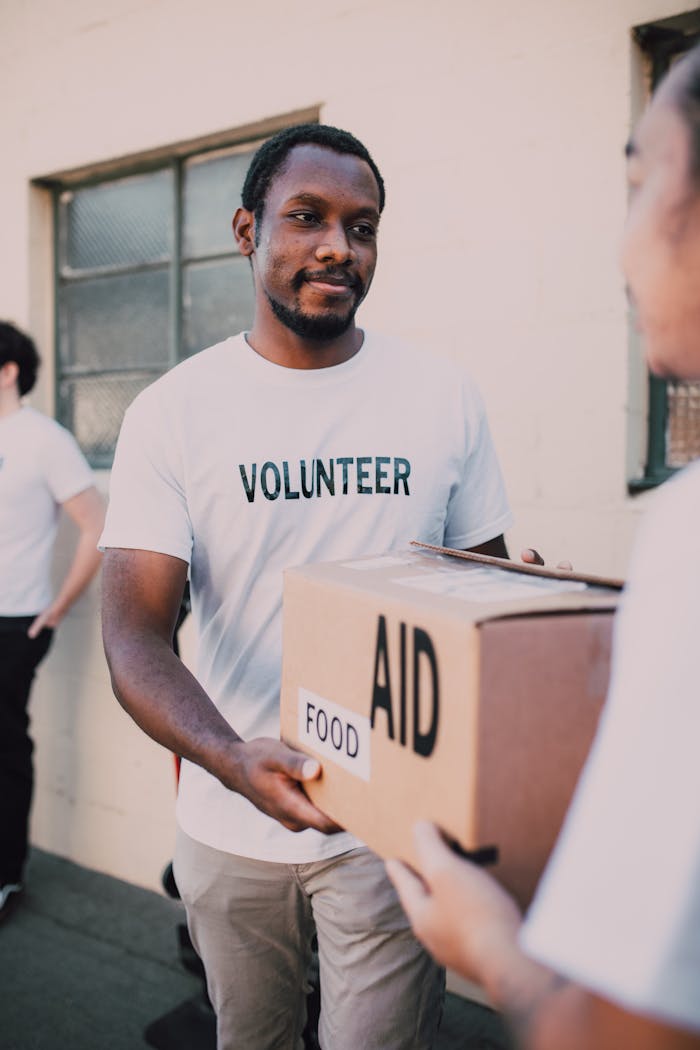 Crafting Captivating Headlines: Your awesome post title goes here A volunteer hands a box labeled 'aid' and 'food' during an outdoor charity event.