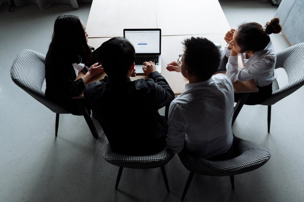 High-angle view of a diverse team collaborating around a laptop in a modern office.